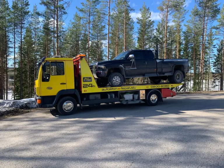 Tiiholan Tokan hinausauto kuljettaa mustaa lava-autoa lavallaan